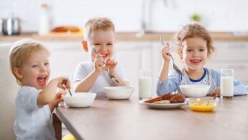 3 children eating on a table
