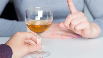 A finger saying no to a glass of alcohol