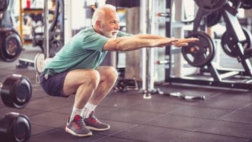 Old man squatting down at the gym